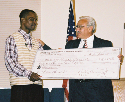 Pastor Charlie presenting John Chambo with donation